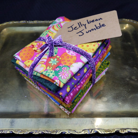 Colorful fabric squares with a decorative bow on a metallic surface, labeled 'Ivy Bean Jelly Bean'.